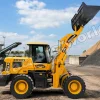 Yellow front-end loader at a construction site raising its bucket filled with earth or gravel in the air