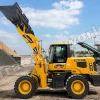 Yellow wheel loader scoops gravel at a quarry with a blue sky and conveyor behind it.